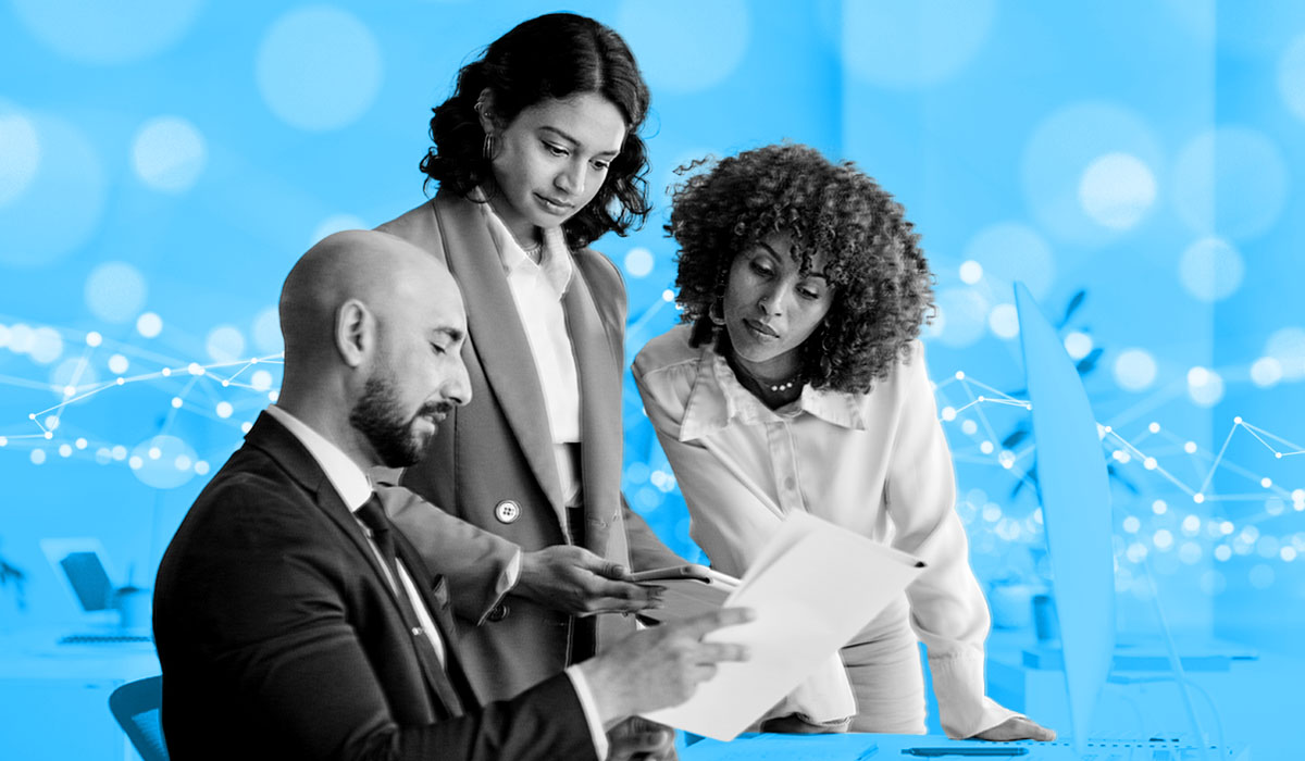 Three people looking at a stack of papers representing employee data management.